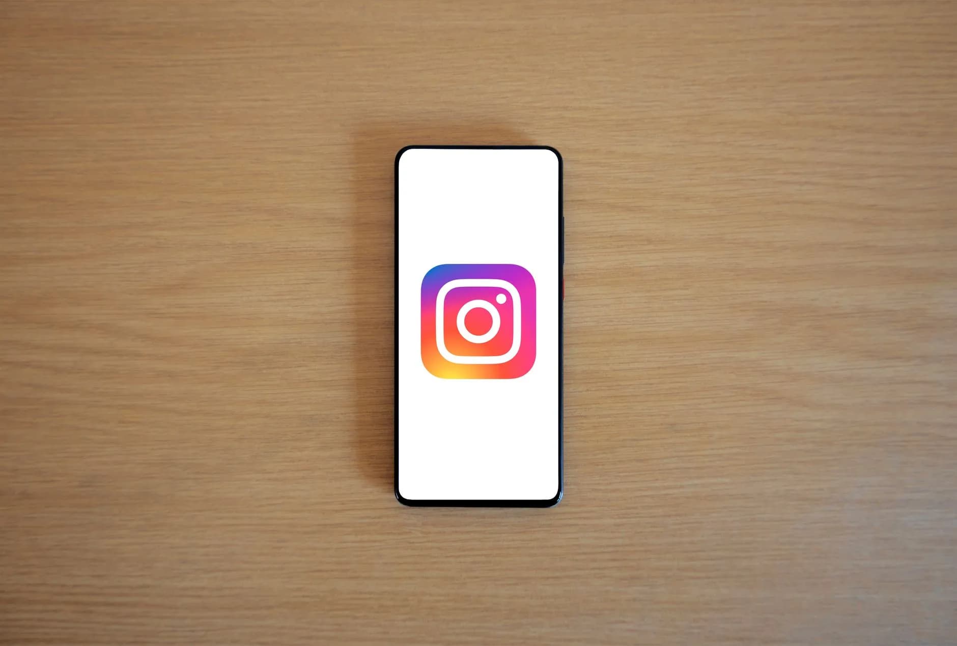 A smartphone with the Instagram logo on display, placed on a wooden surface. Perfect for technology and social media the