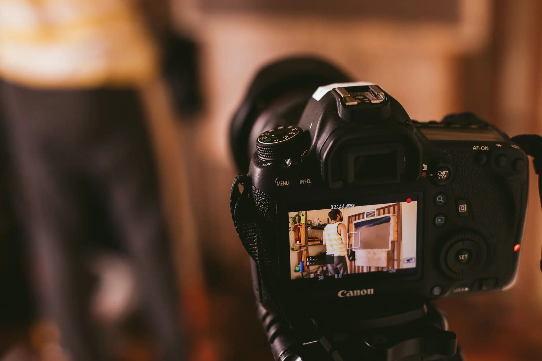 Close-up view of a DSLR camera screen capturing a person in a studio setting, focusing on technology and photography.