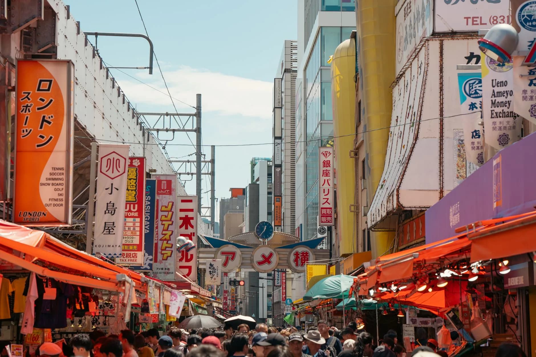 Vibrant street market scene in Ameyoko, Tokyo with colorful signs and bustling crowds.
