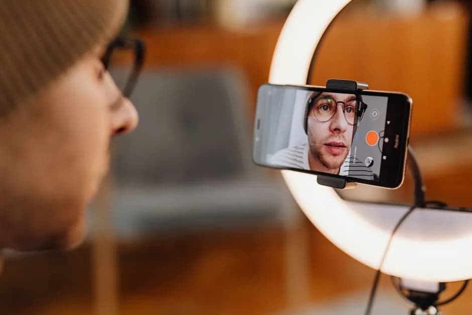 Close-up of a person recording a live video with a smartphone and ring light indoors